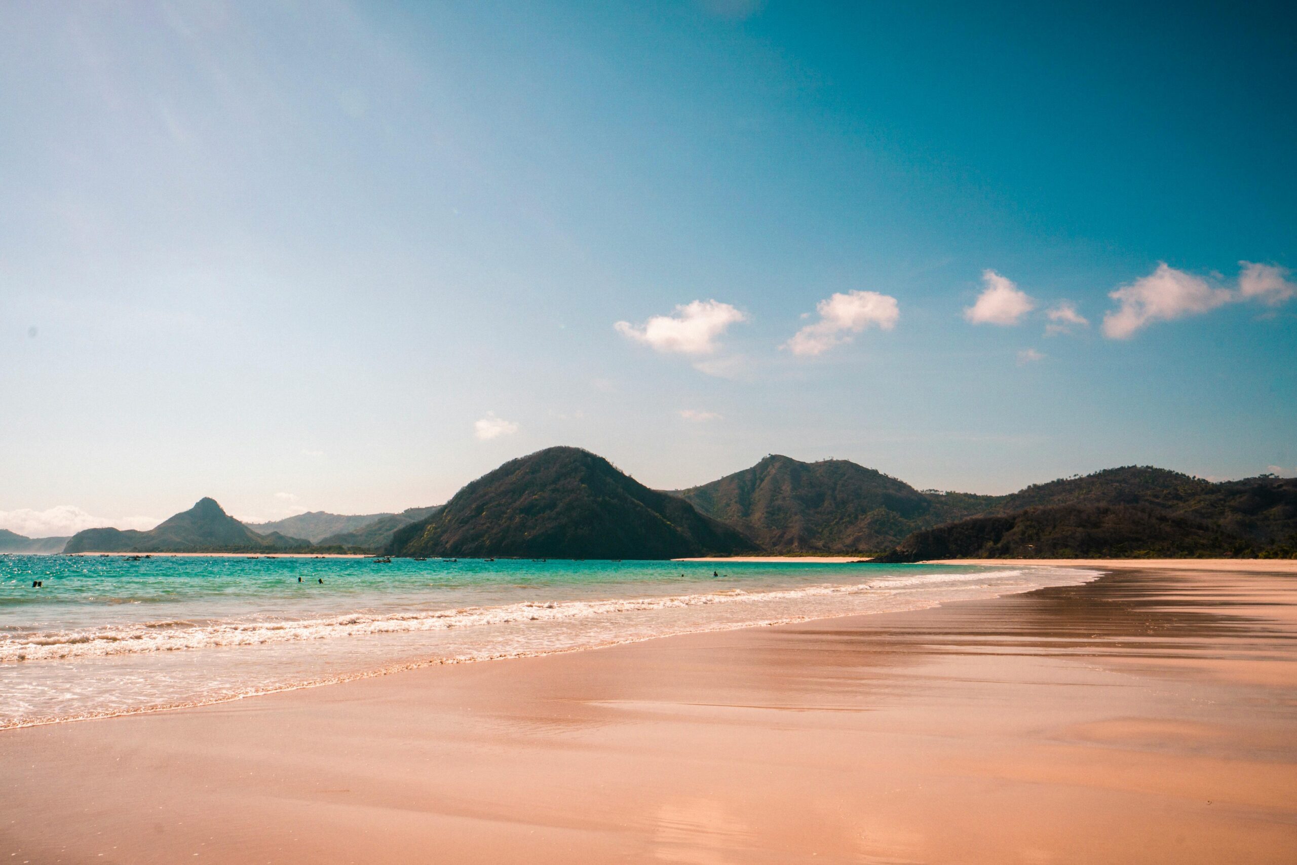 A tranquil beach view with mountains and turquoise water in West Nusa Tenggara, Indonesia.